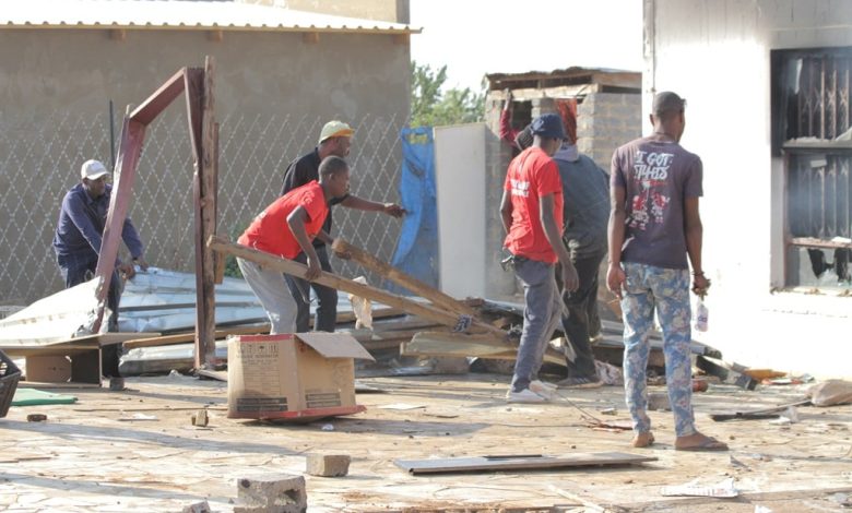 Angry community members looting the tavern of the suspected killer before burning it down. Photo by Tumelo Mofokeng